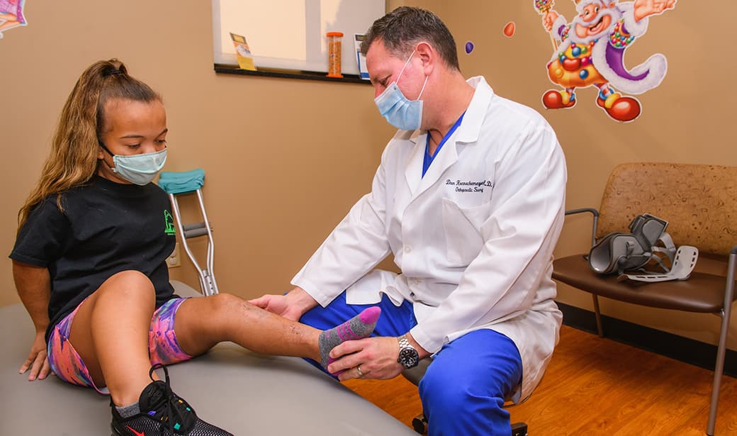 Doctor examining the leg of a child with achondroplasia during an orthopedic visit